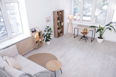 Photo of Stylish living room interior. Sofa, table, shelving unit and other furniture indoors, above view