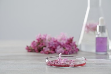 Photo of Making luxury perfume. Essential oils in glassware and flowers on white wooden table, closeup. Space for text
