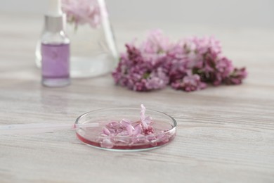 Photo of Making luxury perfume. Essential oils in glassware and flowers on white wooden table, closeup