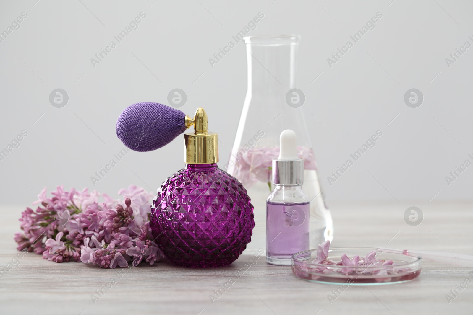 Photo of Making luxury perfume. Essential oils in glassware and flowers on white wooden table, closeup