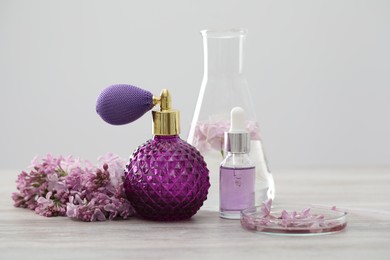 Photo of Making luxury perfume. Essential oils in glassware and flowers on white wooden table, closeup