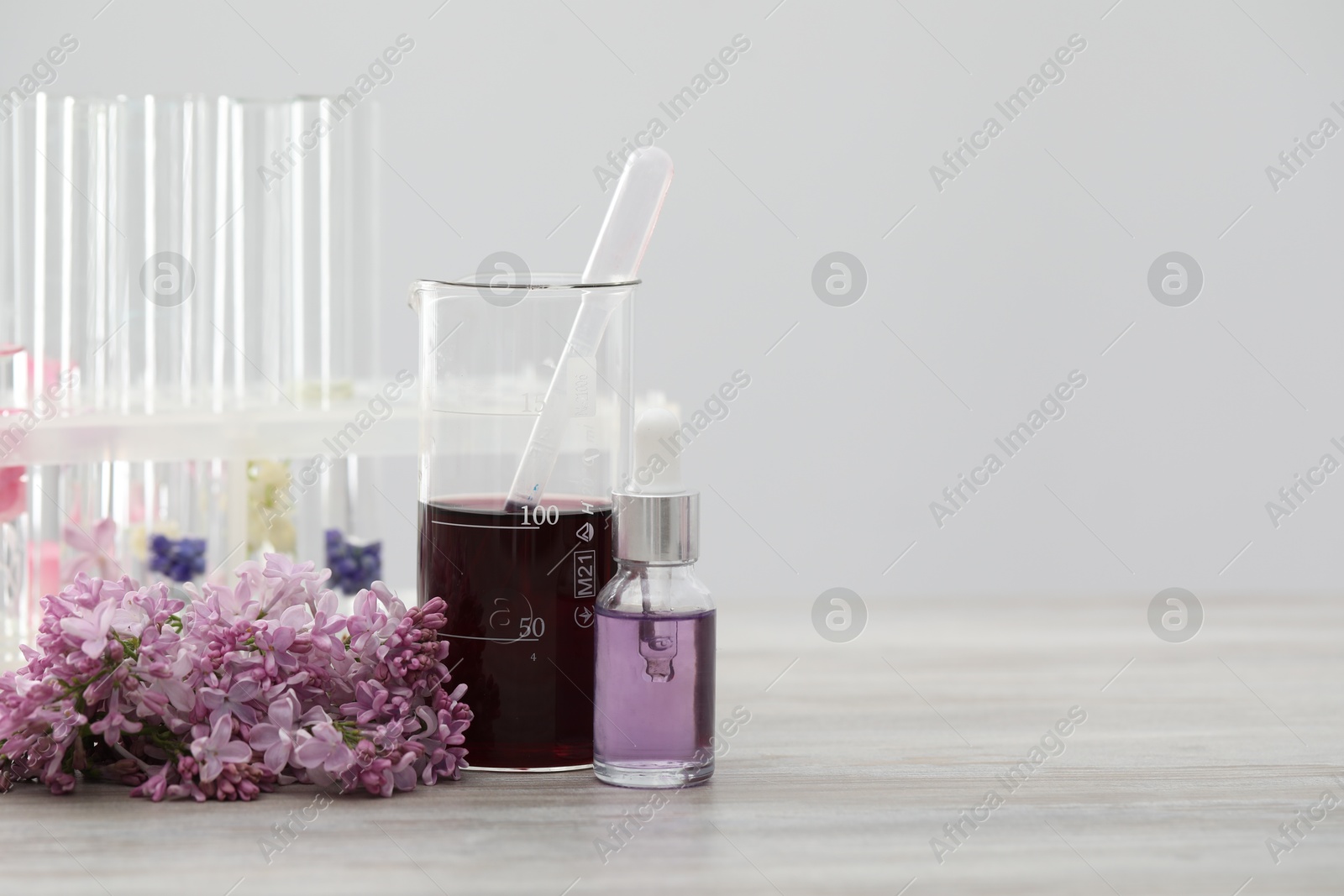 Photo of Making luxury perfume. Essential oils in glassware and flowers on white wooden table, closeup. Space for text