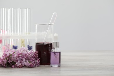 Photo of Making luxury perfume. Essential oils in glassware and flowers on white wooden table, closeup. Space for text