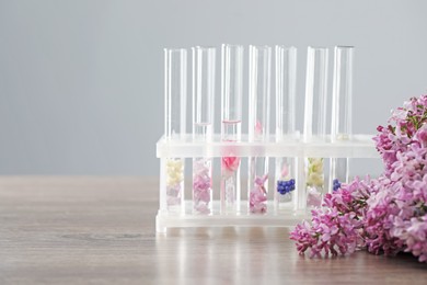 Photo of Making luxury perfume. Essential oils in glassware and flowers on light wooden table, closeup. Space for text