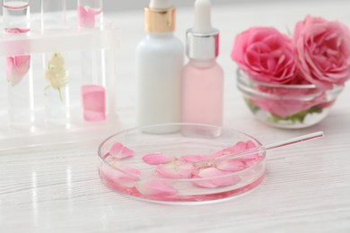 Photo of Making luxury perfume. Essential oils in glassware and flowers on white wooden table, closeup