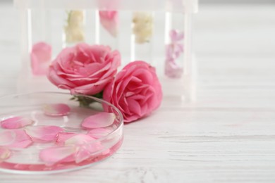 Photo of Making luxury perfume. Essential oils in glassware and flowers on white wooden table, closeup. Space for text