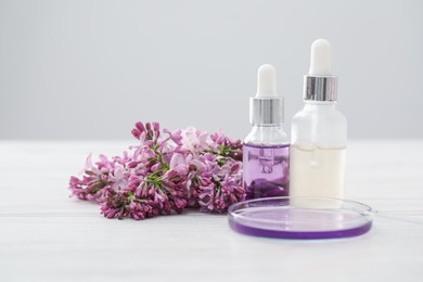 Photo of Making luxury perfume. Essential oils in glassware and flowers on white wooden table, closeup