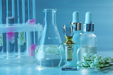 Photo of Making luxury perfume. Essential oils in glassware and flowers on white wooden table, closeup