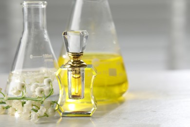 Photo of Making luxury perfume. Essential oils in glassware and flowers on white wooden table, closeup. Space for text