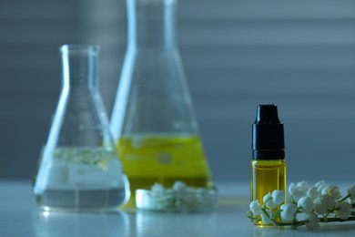 Photo of Making luxury perfume. Essential oils in glassware and flowers on white wooden table, closeup