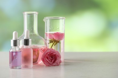 Photo of Making luxury perfume. Essential oils in glassware and flowers on white wooden table against blurred background, closeup. Space for text