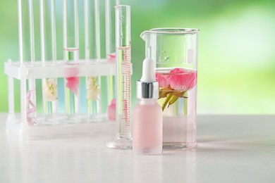 Photo of Making luxury perfume. Essential oils in glassware and flowers on white wooden table against blurred background, closeup
