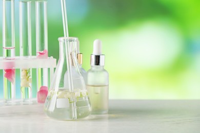 Photo of Making luxury perfume. Essential oils in glassware and flowers on white wooden table against blurred background, closeup. Space for text