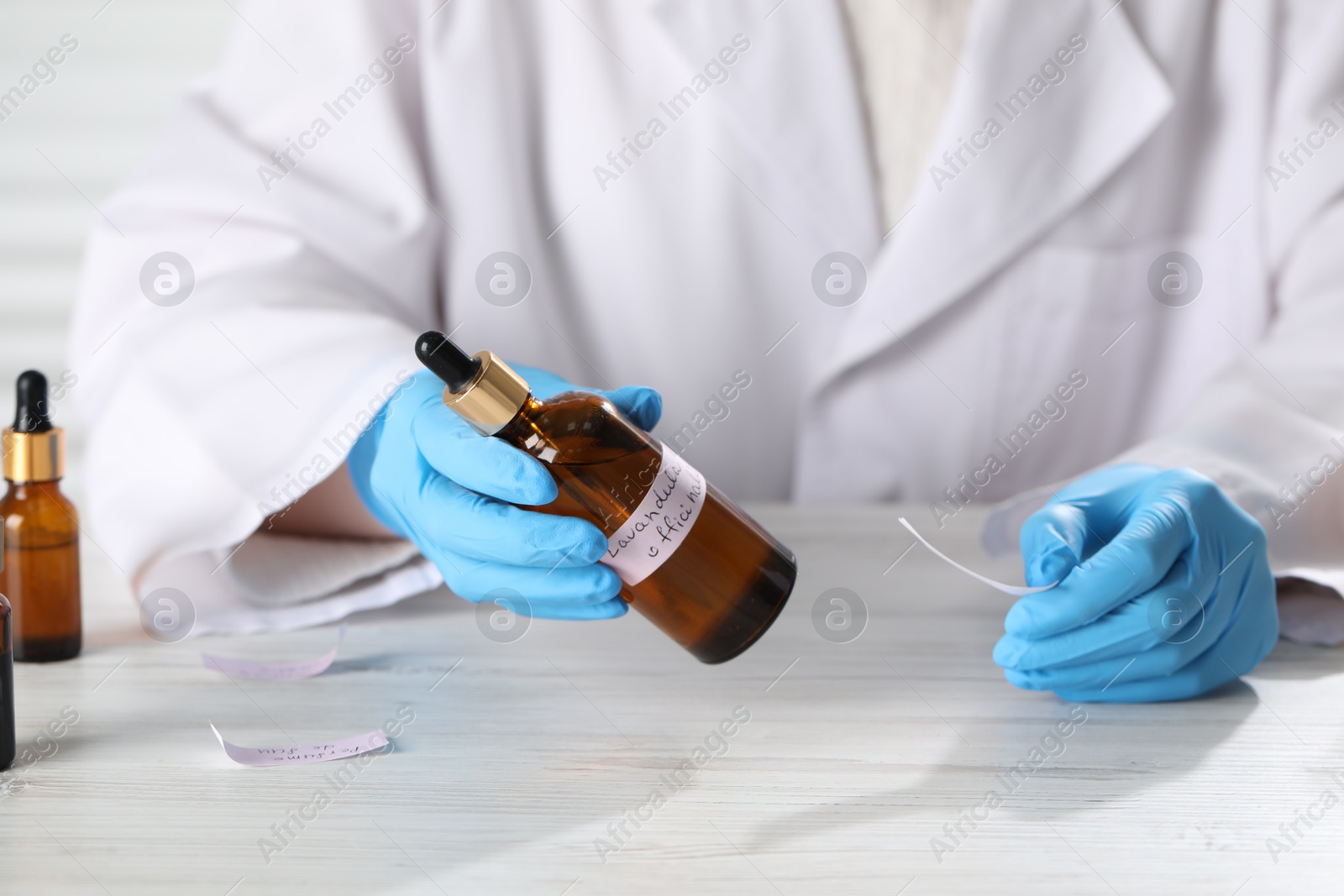 Professional perfumer developing luxury perfume at white wooden table in laboratory, closeup Photo of Professional perfumer developing luxury perfume at white wooden table in laboratory, closeup