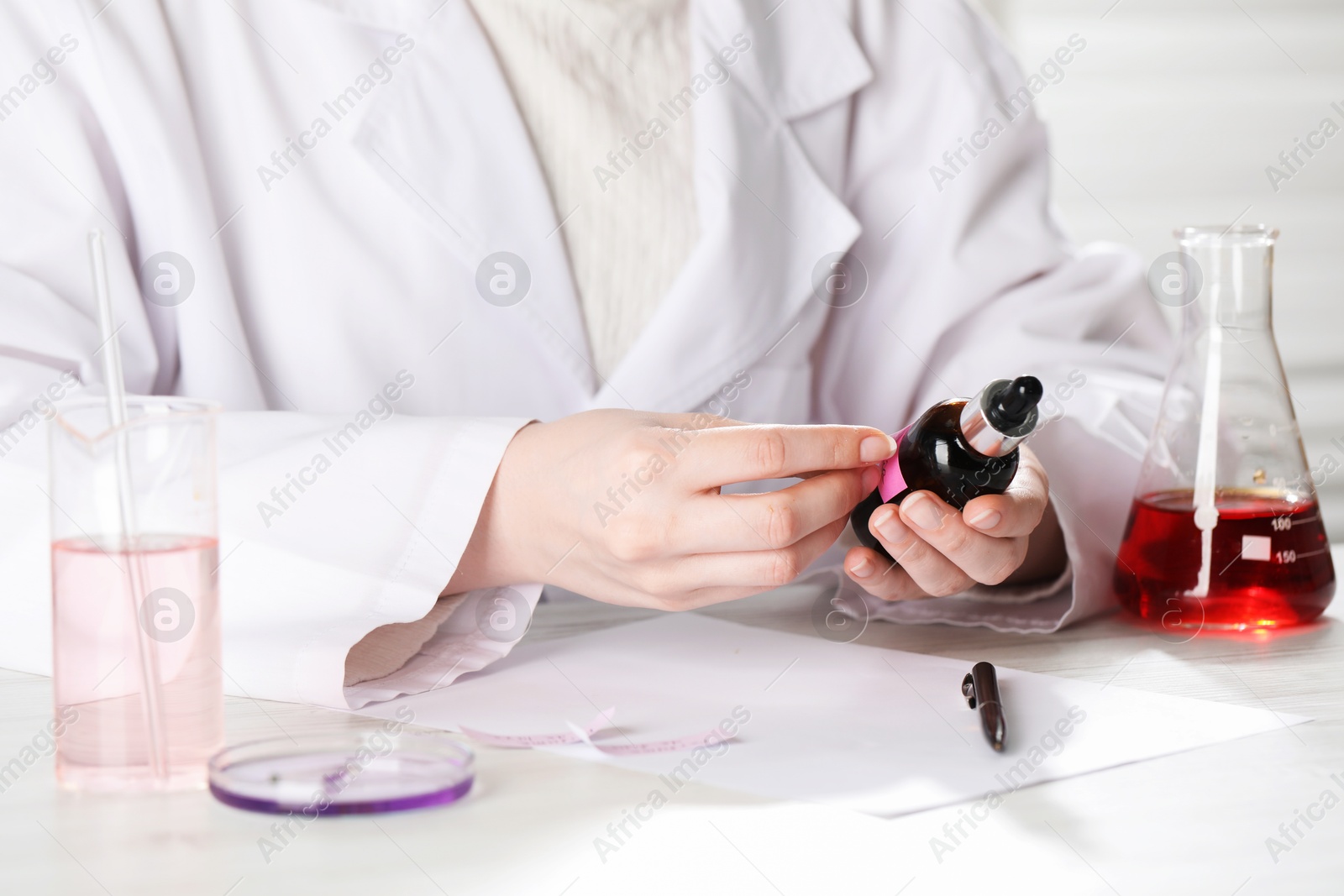 Professional perfumer developing luxury perfume at white wooden table in laboratory, closeup Photo of Professional perfumer developing luxury perfume at white wooden table in laboratory, closeup