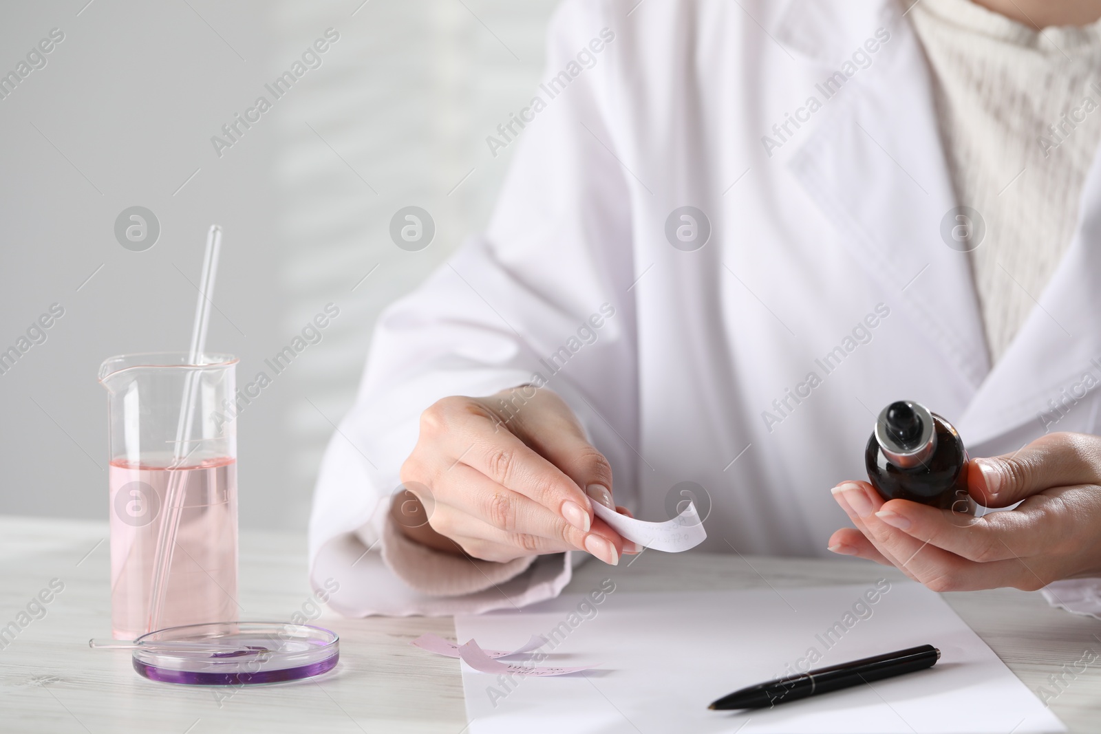 Professional perfumer developing luxury perfume at white wooden table in laboratory, closeup Photo of Professional perfumer developing luxury perfume at white wooden table in laboratory, closeup