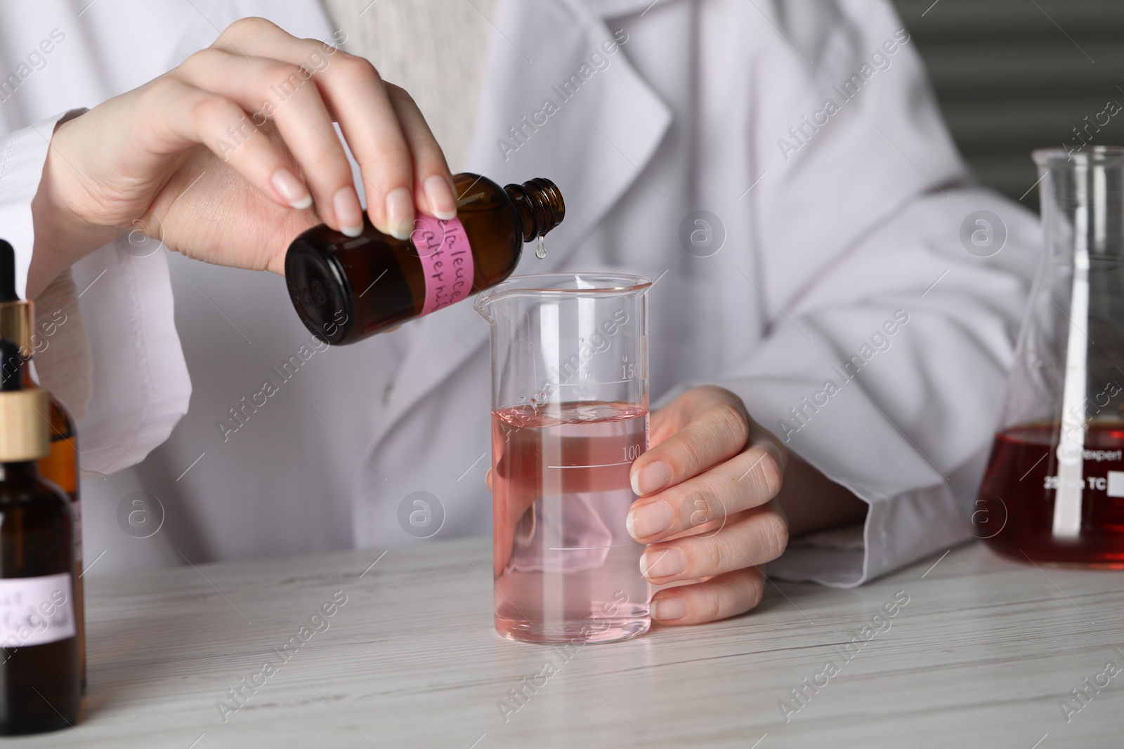 Professional perfumer developing luxury perfume at white wooden table in laboratory, closeup Photo of Professional perfumer developing luxury perfume at white wooden table in laboratory, closeup