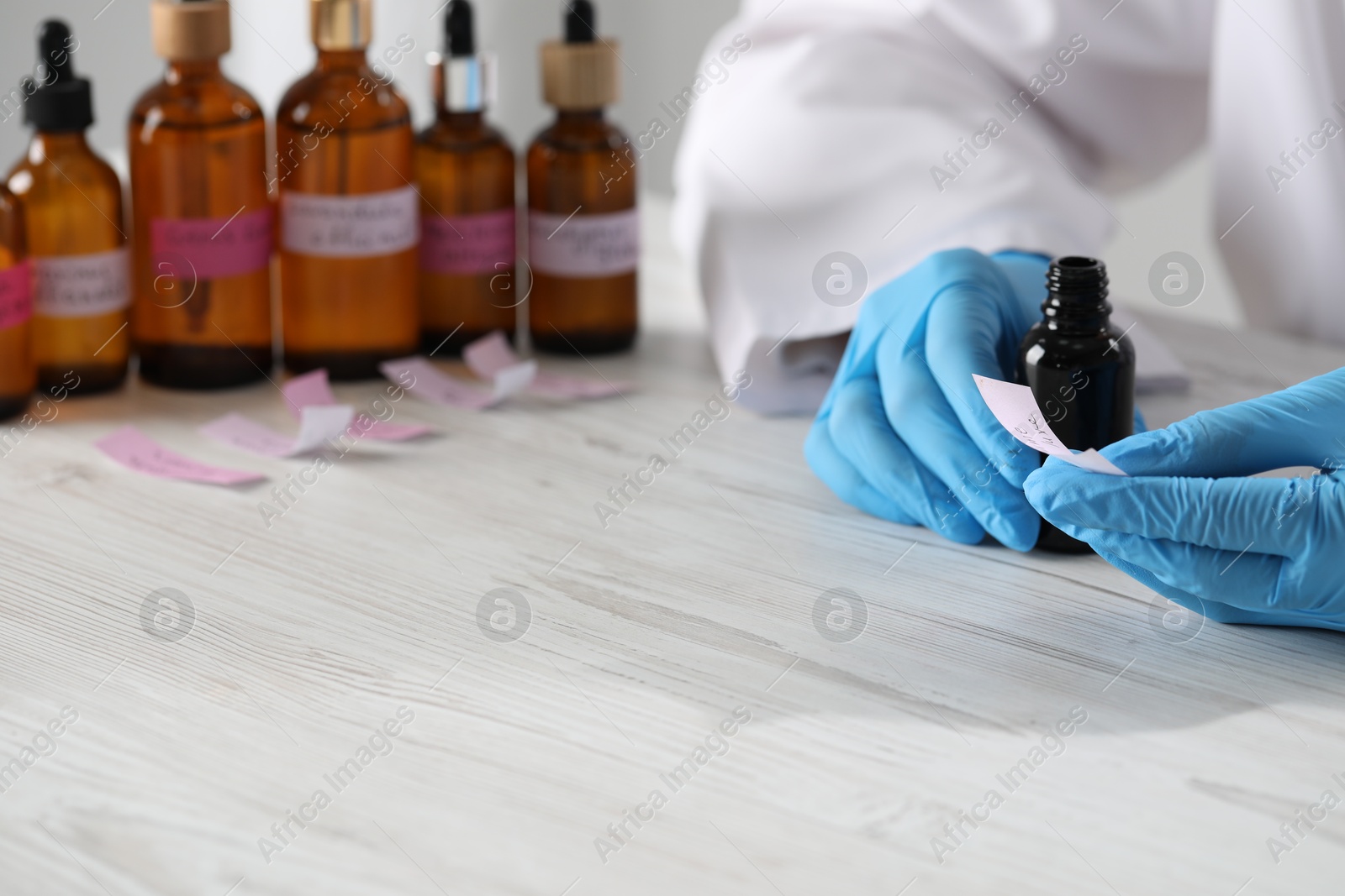 Professional perfumer developing luxury perfume at white wooden table in laboratory, closeup Photo of Professional perfumer developing luxury perfume at white wooden table in laboratory, closeup