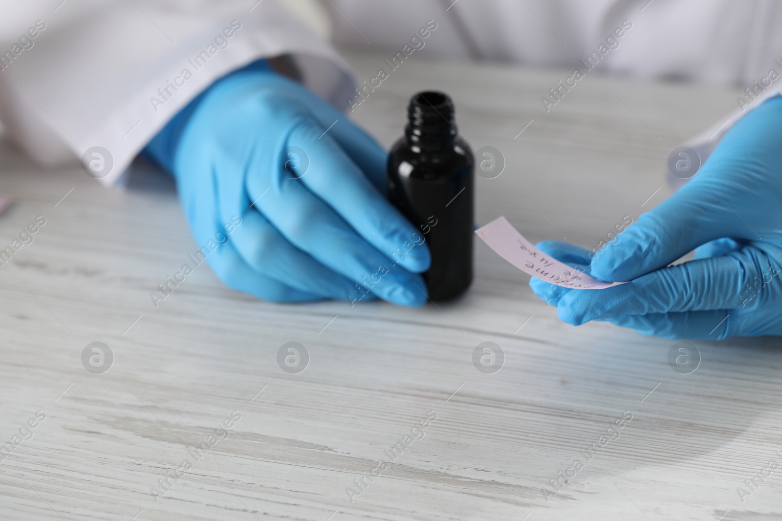 Professional perfumer developing luxury perfume at white wooden table in laboratory, closeup Photo of Professional perfumer developing luxury perfume at white wooden table in laboratory, closeup