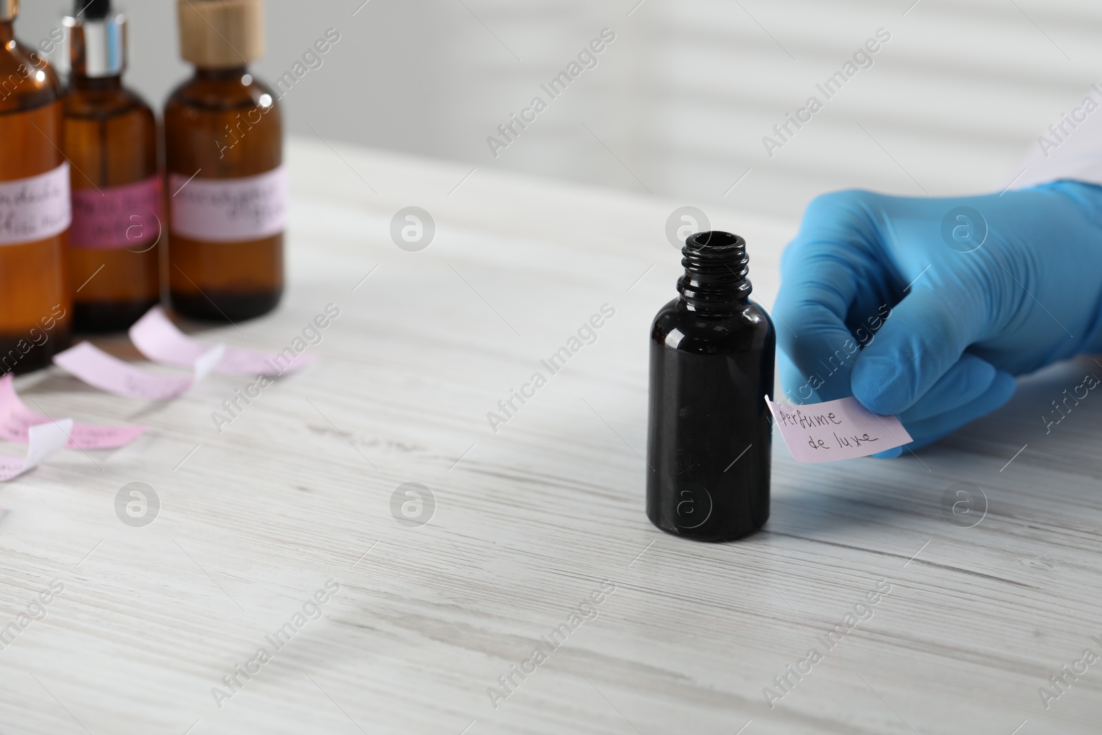 Professional perfumer developing luxury perfume at white wooden table in laboratory, closeup Photo of Professional perfumer developing luxury perfume at white wooden table in laboratory, closeup