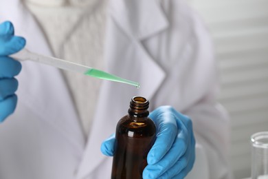 Photo of Professional perfumer developing luxury perfume in laboratory, closeup