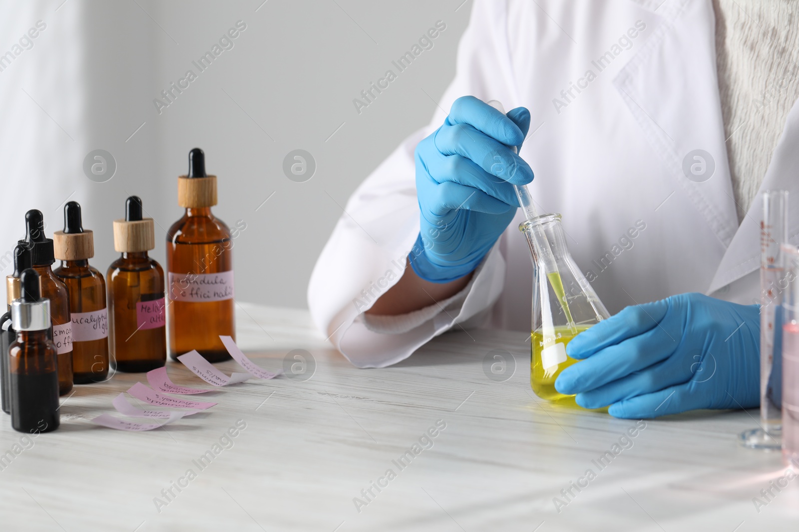 Professional perfumer developing luxury perfume at white wooden table in laboratory, closeup Photo of Professional perfumer developing luxury perfume at white wooden table in laboratory, closeup