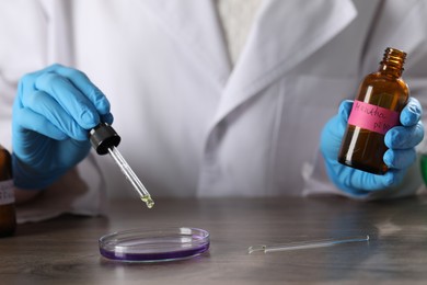 Photo of Professional perfumer developing luxury perfume at wooden table in laboratory, closeup