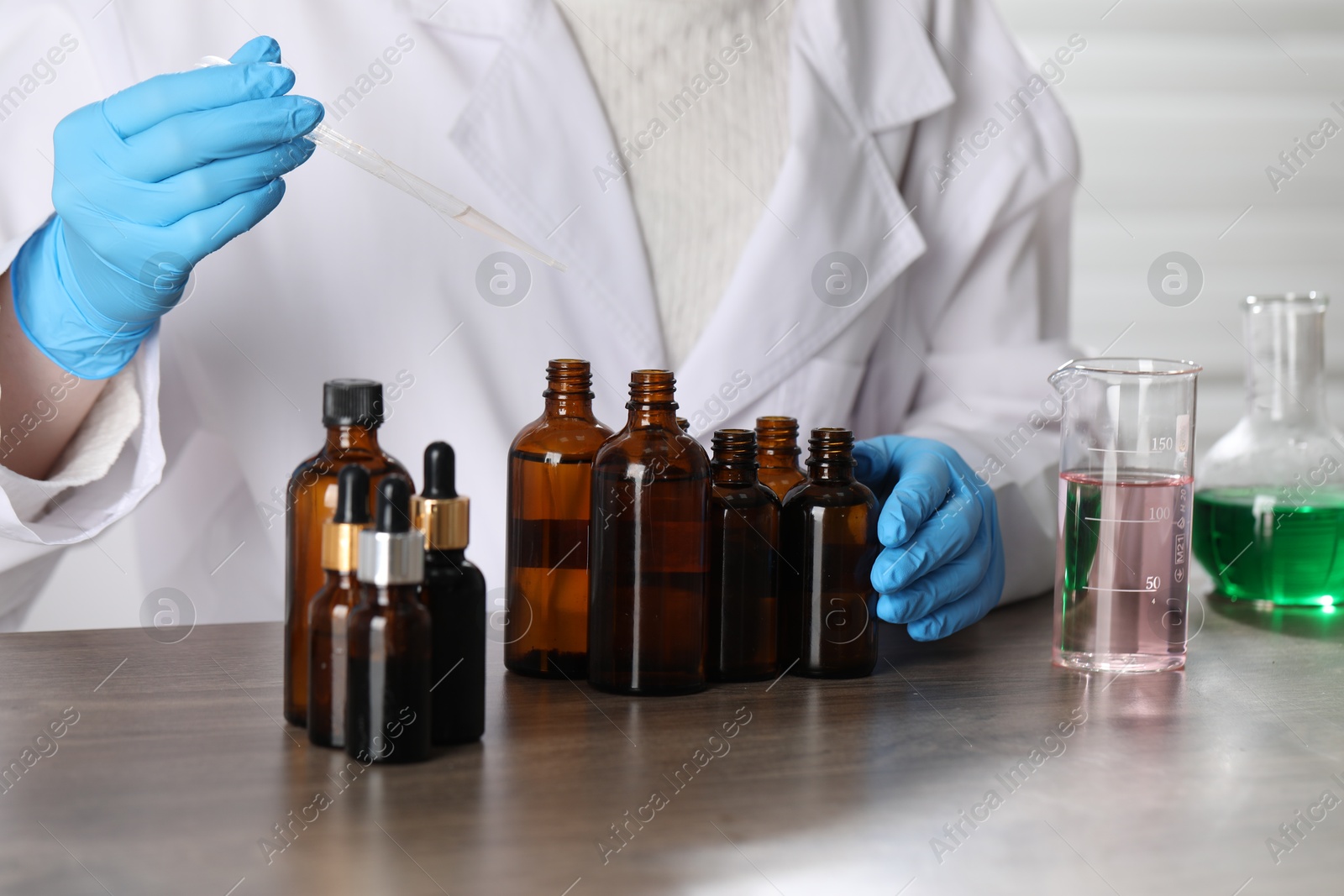 Professional perfumer developing luxury perfume at wooden table in laboratory, closeup Photo of Professional perfumer developing luxury perfume at wooden table in laboratory, closeup
