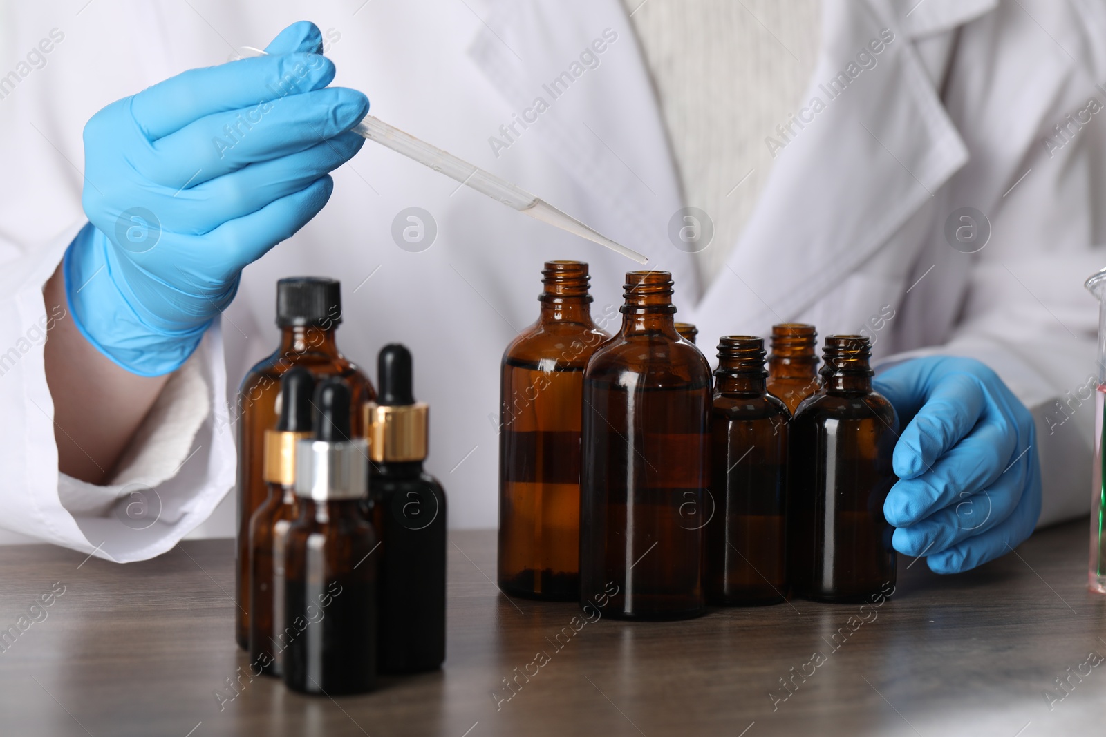 Professional perfumer developing luxury perfume at wooden table in laboratory, closeup Photo of Professional perfumer developing luxury perfume at wooden table in laboratory, closeup