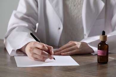 Photo of Professional perfumer developing luxury perfume at wooden table in laboratory, closeup