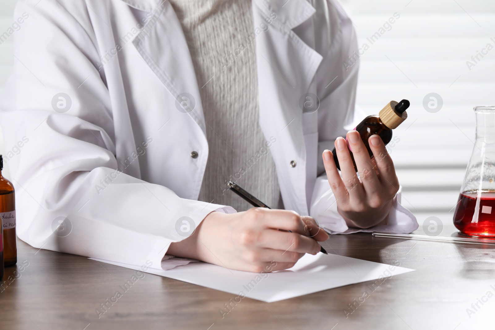 Professional perfumer developing luxury perfume at wooden table in laboratory, closeup Photo of Professional perfumer developing luxury perfume at wooden table in laboratory, closeup