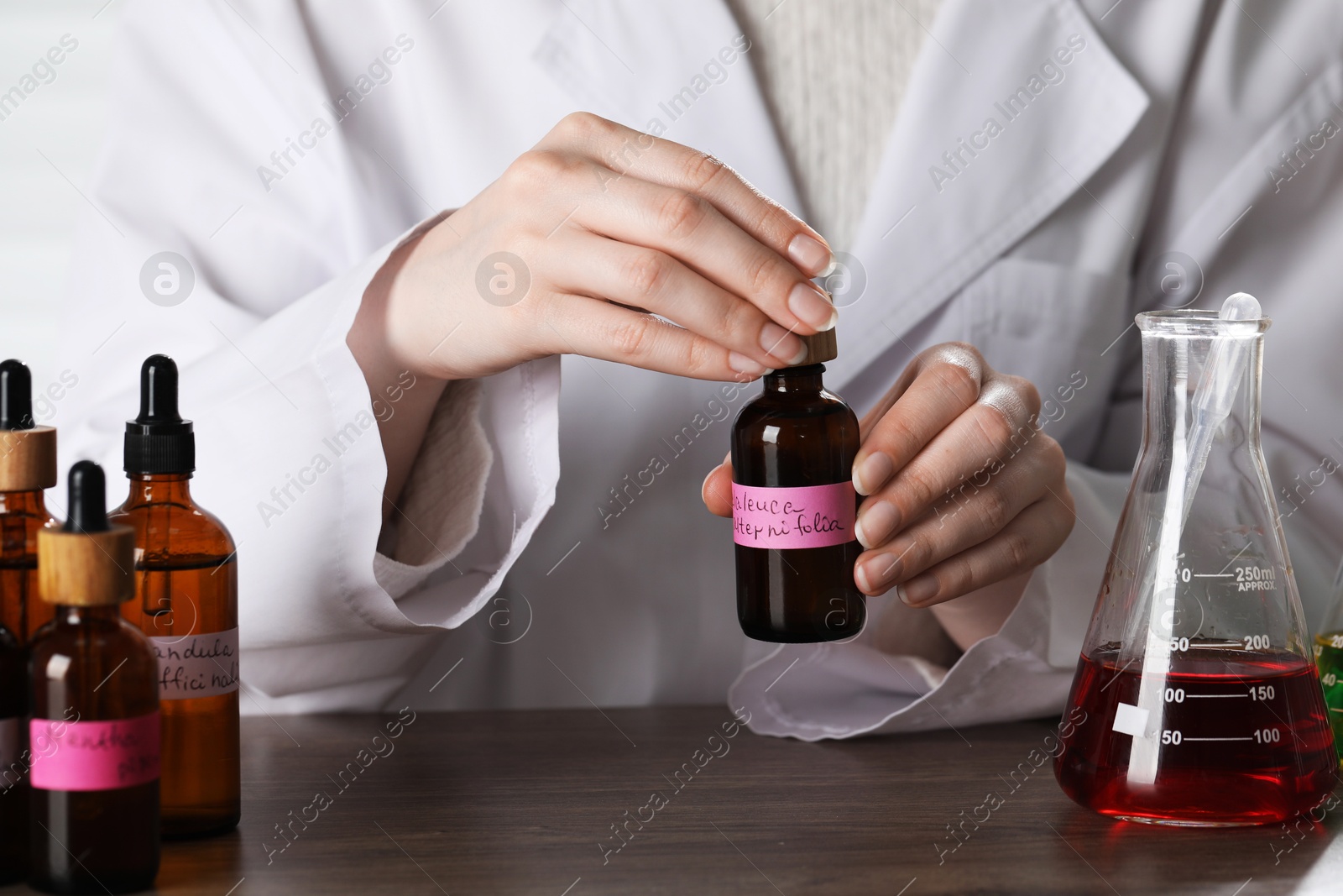 Professional perfumer developing luxury perfume at wooden table in laboratory, closeup Photo of Professional perfumer developing luxury perfume at wooden table in laboratory, closeup