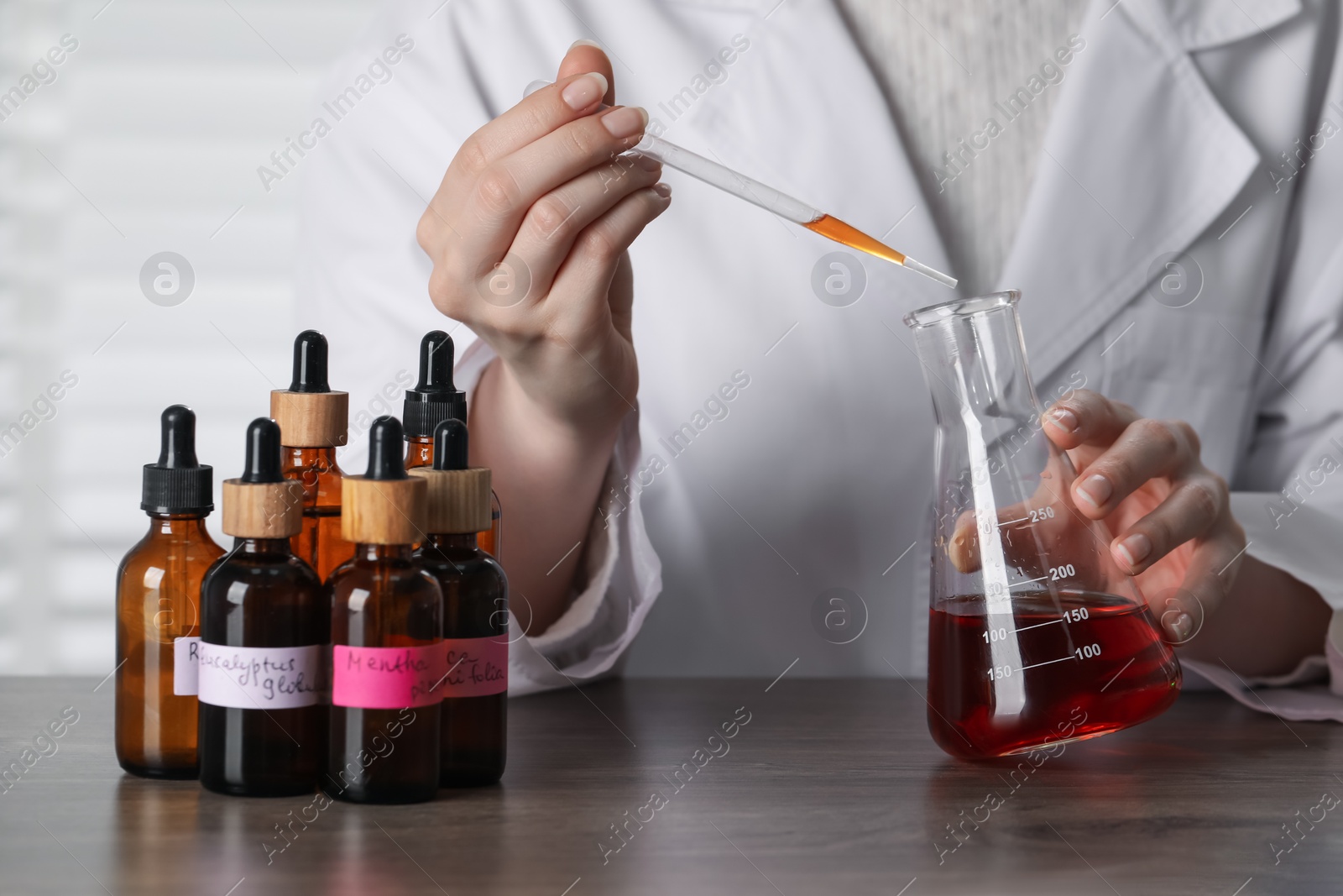 Professional perfumer developing luxury perfume at wooden table in laboratory, closeup Photo of Professional perfumer developing luxury perfume at wooden table in laboratory, closeup