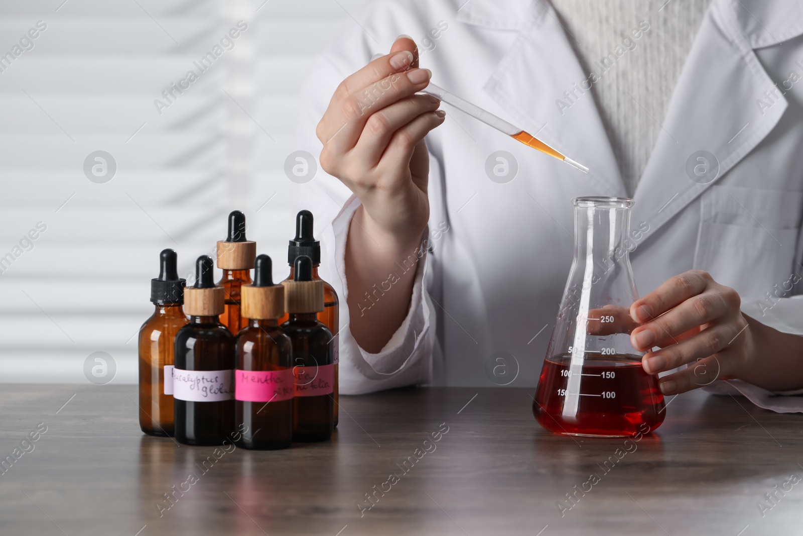 Professional perfumer developing luxury perfume at wooden table in laboratory, closeup Photo of Professional perfumer developing luxury perfume at wooden table in laboratory, closeup