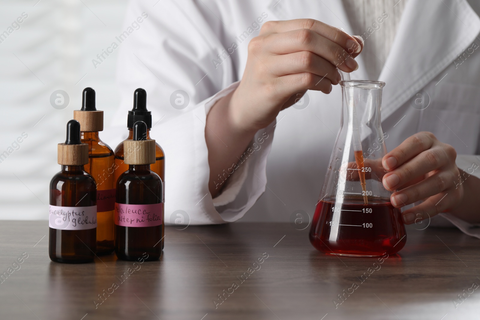 Professional perfumer developing luxury perfume at wooden table in laboratory, closeup Photo of Professional perfumer developing luxury perfume at wooden table in laboratory, closeup