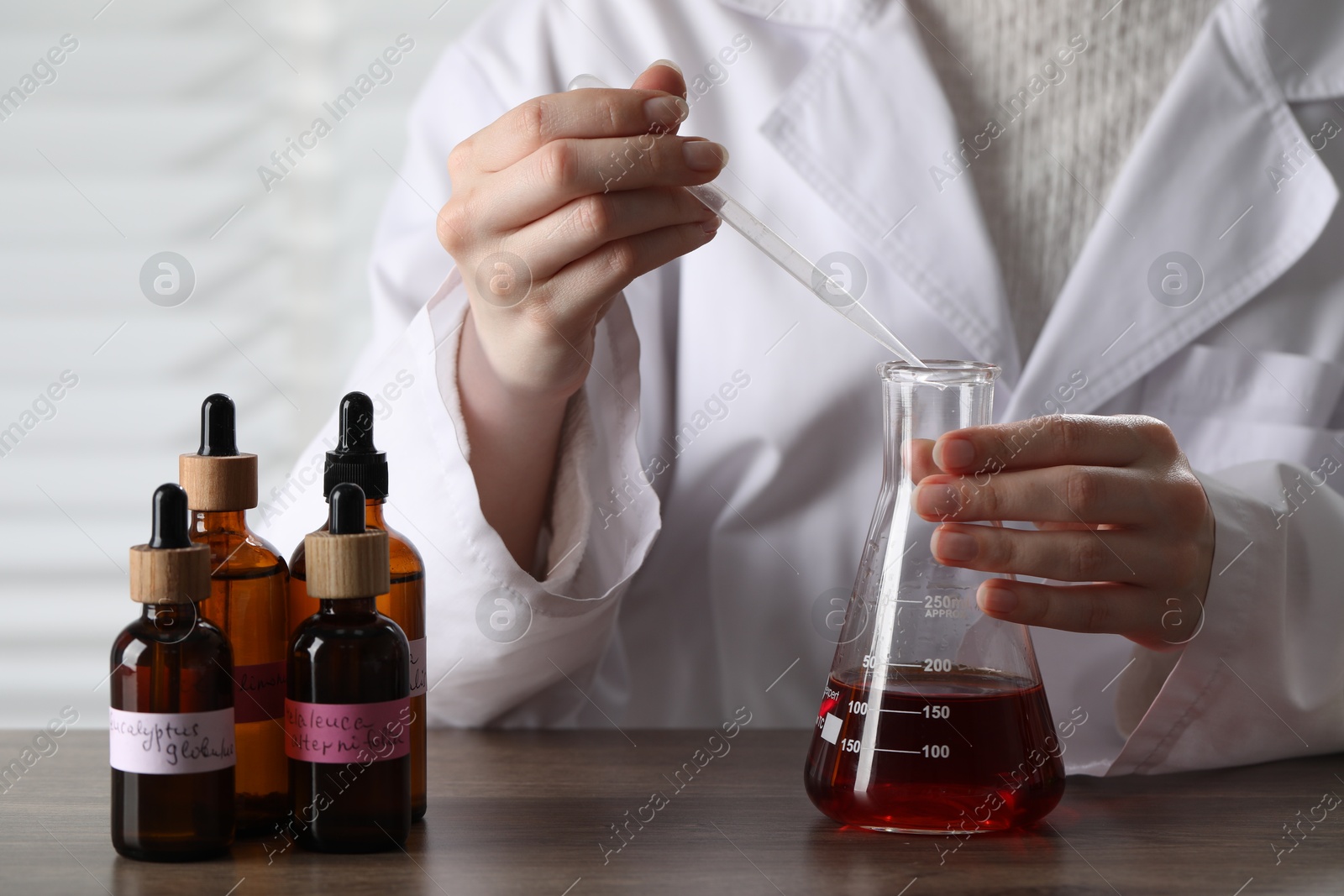Professional perfumer developing luxury perfume at wooden table in laboratory, closeup Photo of Professional perfumer developing luxury perfume at wooden table in laboratory, closeup