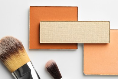 Photo of Beautiful eyeshadow refill pans and brushes on white background, flat lay