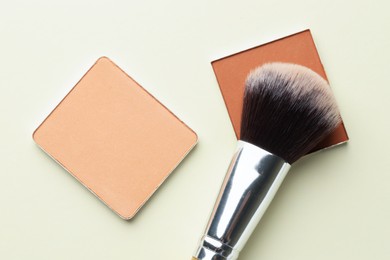 Photo of Beautiful eyeshadow refill pans and brush on beige background, flat lay