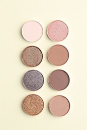 Photo of Beautiful eyeshadow refill pans on beige background, flat lay