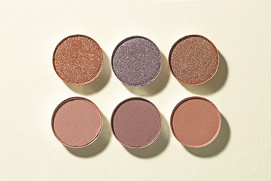 Photo of Beautiful eyeshadow refill pans on beige background, flat lay