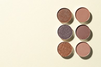 Photo of Beautiful eyeshadow refill pans on beige background, flat lay. Space for text