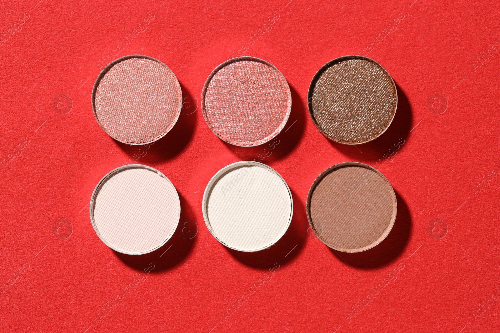 Beautiful eyeshadow refill pans on red background, flat lay Photo of Beautiful eyeshadow refill pans on red background, flat lay