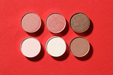 Photo of Beautiful eyeshadow refill pans on red background, flat lay