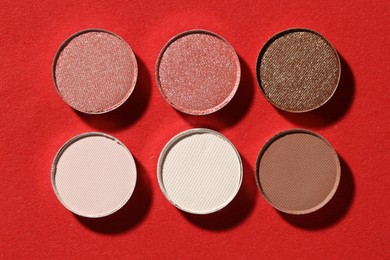 Photo of Beautiful eyeshadow refill pans on red background, flat lay