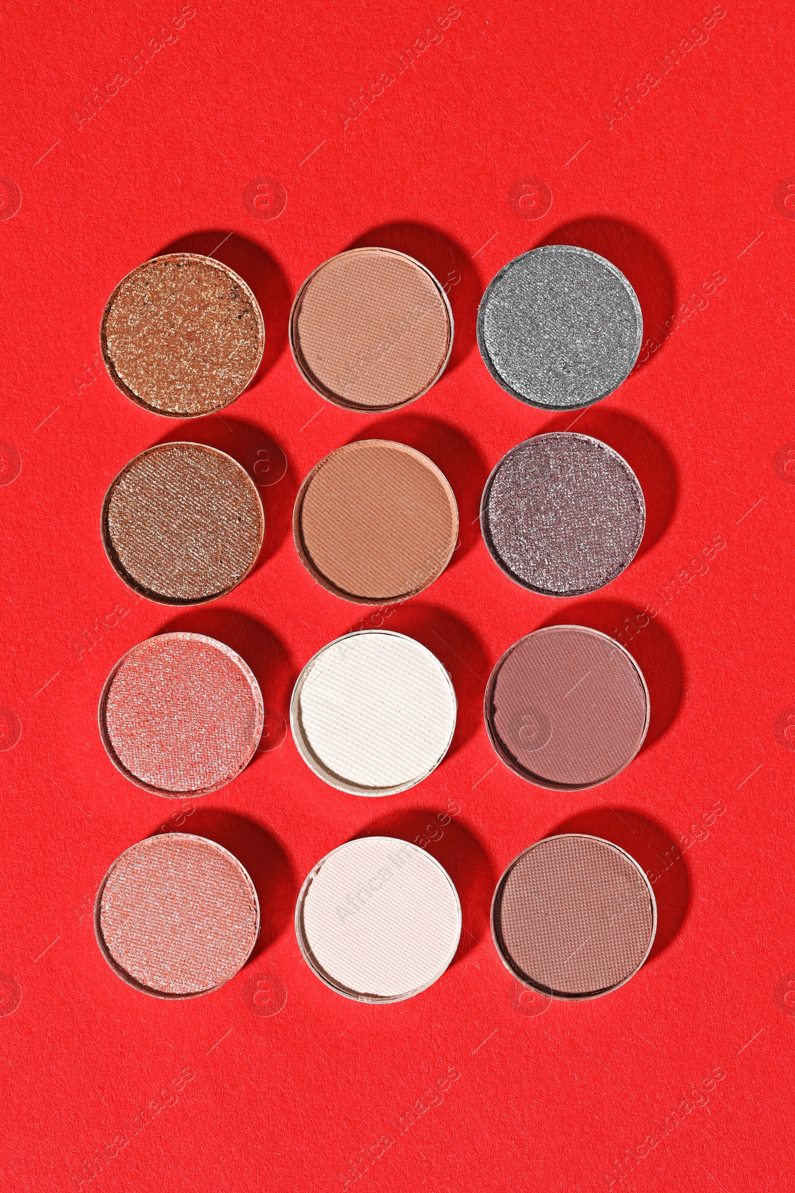 Beautiful eyeshadow refill pans on red background, flat lay Photo of Beautiful eyeshadow refill pans on red background, flat lay
