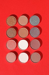 Photo of Beautiful eyeshadow refill pans on red background, flat lay