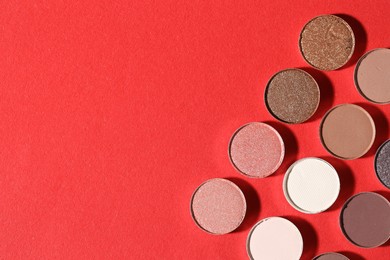 Photo of Beautiful eyeshadow refill pans on red background, flat lay. Space for text