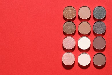 Photo of Beautiful eyeshadow refill pans on red background, flat lay. Space for text