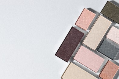 Photo of Beautiful eyeshadow refill pans on light background, flat lay. Space for text