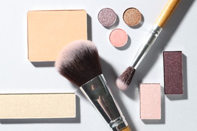 Photo of Beautiful eyeshadow refill pans and brushes on light background, flat lay